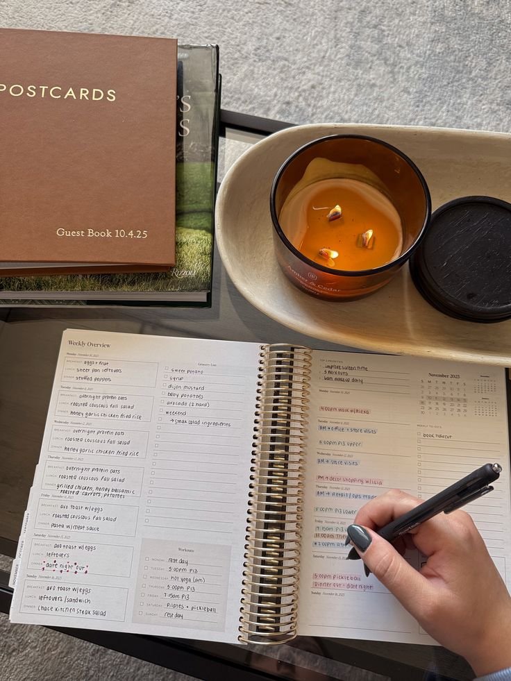 Open weekly planner with handwritten schedule beside candle and books, representing time management planning and daily productivity habits.